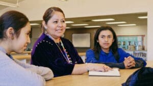 Teacher pointing to notebook while at table with students